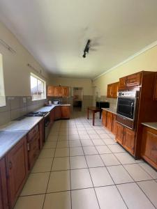 a large kitchen with wooden cabinets and a tile floor at NamaStay in Vereeniging