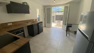 a kitchen with a sink and a table and a refrigerator at La perle de provence, appartement neuf en rez de Jardin clos, au calme, clim, salle d'eau dans chaque chambre, à 900m du centre de Nyons in Nyons +10 photos