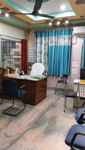 Bikash Bhawan Lodge في سيليغري: مكتب فيه مكتب وكراسي في الغرفة