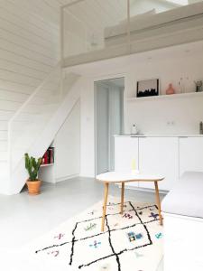 a white living room with a table and a rug at Tiny House d'exception au bord de mer in La Bernerie-en-Retz