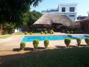 a resort with a swimming pool and a thatch hut at Sparkle Guest House - Self-Catering, Pool, Garden in Maputo