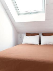 a bedroom with a bed with two pillows and a window at Tiny House d'exception au bord de mer in La Bernerie-en-Retz