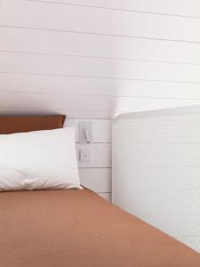 1 dormitorio con 1 cama con almohada blanca en Tiny House d'exception au bord de mer en La Bernerie-en-Retz