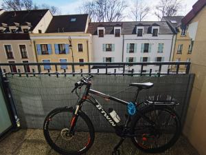 ein Fahrrad neben einem Zaun mit Gebäuden geparkt in der Unterkunft Versailles Trip Appartement in Buc