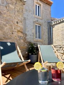 a table with two chairs and drinks on a patio at La Maison du Puits in Cesseras