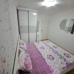 een kleine slaapkamer met een bed met een paarse deken bij Jove Apartments in Bitola