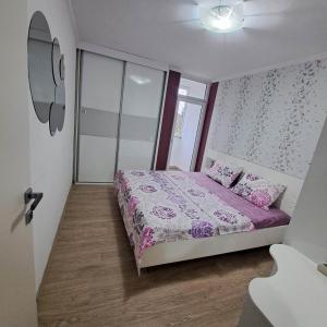 Schlafzimmer mit einem Bett mit lila Bettwäsche und Kissen in der Unterkunft Jove Apartments in Bitola