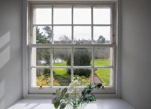 una ventana abierta con un jarrón de flores sobre una mesa en The Clock Tower en Selkirk