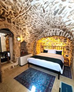 1 dormitorio con cama y pared de piedra en TUĞMANER Small House AJAR en Mardin