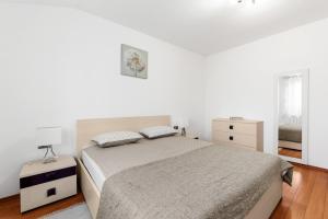 een witte slaapkamer met een bed en een nachtkastje bij Villa Lori in Nova Vas