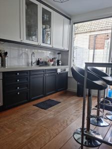 a kitchen with black cabinets and a bar stool at Cosy & modern 3 bedroom house close to the beach in Katwijk aan Zee