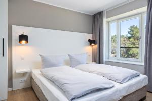 - une chambre avec un grand lit blanc et une fenêtre dans l'établissement Strandresidenzen Strandresidenzen Haus Dänholm 2 2, à Binz