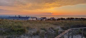 a sunset over a beach with houses and the ocean at Cosy & modern 3 bedroom house close to the beach in Katwijk aan Zee