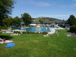 a group of people laying on the grass near a swimming pool at Ferienwohnung Diemelgarten in Willingen