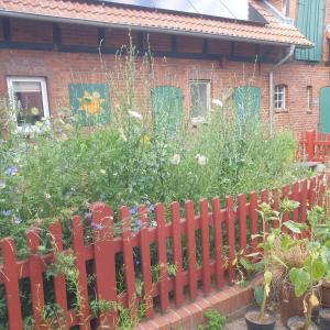 einen roten Zaun vor einem Garten mit Blumen in der Unterkunft radlerunterkunft Grabau Nr.1 