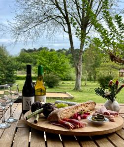 una mesa de madera con un plato de comida y dos botellas de vino en Laguillotte, en Seignosse