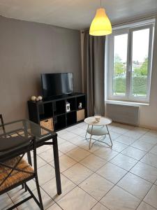 uma sala de estar com uma televisão e uma mesa em appartement duplex proche de la gare et du centre ville em Saint-Omer