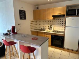 una cucina con frigorifero bianco e sgabelli rossi da bar di appartement duplex proche de la gare et du centre ville a Saint-Omer Altre 19 foto