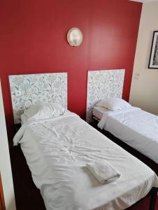 contact hôtel Le Temps Perdu في Le Bois de Cise: سريرين في غرفة ذات جدار احمر