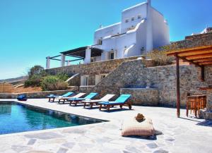 a swimming pool with lounge chairs next to a building at Villas Kappas in Agios Sostis Mykonos