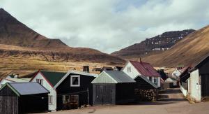 eine kleine Stadt mit Häusern und Bergen im Hintergrund in der Unterkunft Cozy Cottage / 3BR / Hiking / Nature in Við Gjógv