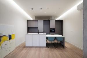 a kitchen with white cabinets and blue chairs at Cosy Loft's Valencia in Catarroja