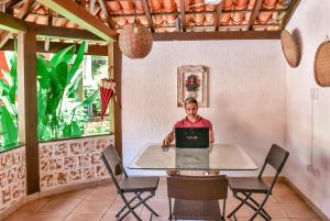 a man sitting at a table with a laptop at Villa Samoa - Ilhabela in Ilhabela