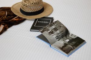 a straw hat next to a book and a magazine at Rephael House Boutique Hotel in Rishon LeẔiyyon