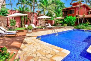 a swimming pool in a yard with chairs and a house at Villa Samoa - Ilhabela in Ilhabela