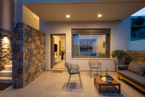 a patio with a stone wall and two chairs and a couch at Blue Cove Zen in Elounda