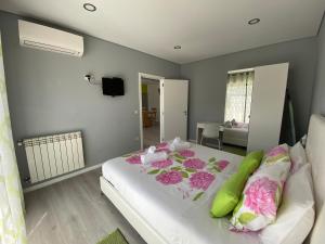 1 dormitorio con 1 cama con almohadas rosas y verdes en Cantinho Verde T1, en Gerês