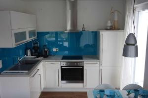 eine Küche mit weißen Schränken und blauen Wänden in der Unterkunft Strandgut in Häven