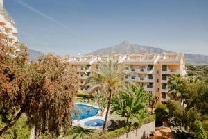 - Vistas a un hotel con piscina y palmeras en Modern apartment with terrace, en Marbella
