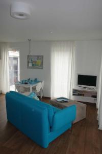 ein Wohnzimmer mit einem blauen Sofa und einem TV in der Unterkunft Strandgut in Häven