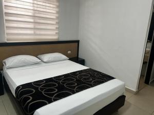 a bedroom with a bed with a black and white blanket at Apartahotel y Hotel Sofichic Boutique in Barranquilla