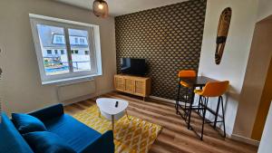 een woonkamer met een blauwe bank en een tafel bij Logements neufs à Bannalec Centre in Bannalec