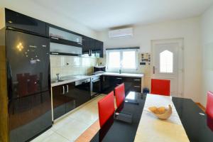 a kitchen with red chairs and a black table and a counter at Bella in Sinj