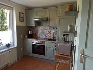 a kitchen with white cabinets and a stove top oven at Ferienhaus Liwi in Liessow