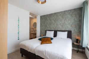 a bedroom with a large white bed and a wall at Maxime 296 - Kustpark Village Scaldia in Hoofdplaat