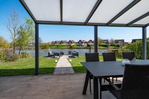 a patio with a table and chairs overlooking a lake at Maxime 296 - Kustpark Village Scaldia in Hoofdplaat