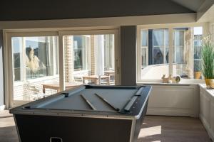 a pool table in a room with windows at Strandhotel Nassau-Bergen in Bergen aan Zee