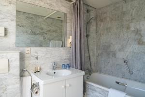 a bathroom with a sink and a tub and a mirror at Strandhotel Nassau-Bergen in Bergen aan Zee