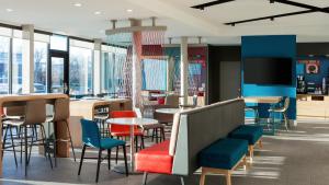 um restaurante com cadeiras coloridas, mesas e janelas em avid hotels - Fort Worth Downtown em Fort Worth