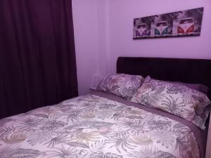 ein Bett in einem Schlafzimmer mit einer Bettdecke mit Blumen in der Unterkunft Precioso apartamento en Santander cerca de todo in Santander