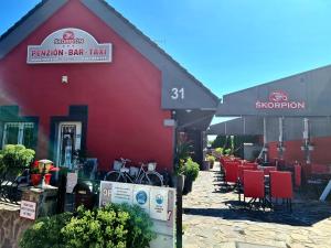 a red building with tables and chairs in front of it at Penzion Škorpión in Senec