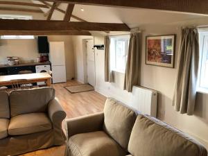 a living room with a couch and a table and windows at The Cowshed in Salisbury