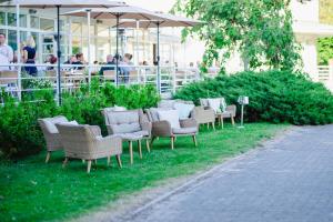 a row of chairs sitting in the grass near a building at Rannahotell in Pärnu