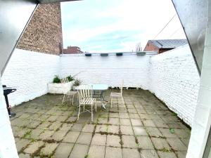 eine Terrasse mit einem Tisch und Stühlen sowie einer weißen Ziegelwand in der Unterkunft Au logement mosan in Namur