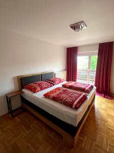 um quarto com uma cama com almofadas vermelhas e uma janela em Apartment Mia em Neusiedl am See