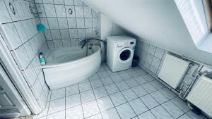 een badkamer met een bad en een wasmachine bij Apartament Pod Kasztanami - BIAŁY in Ińsko